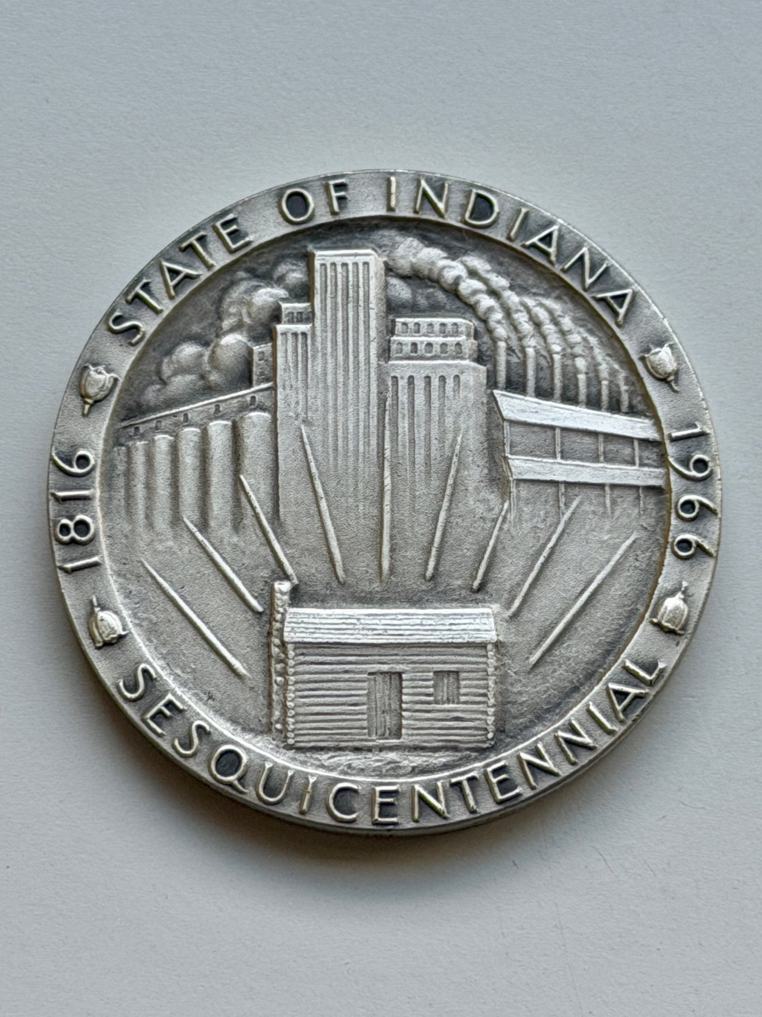Indiana Sesquicentennial Commemorative Medal (1816–1966): This brass medal celebrates the 150th anniversary of Indiana's statehood (1816–1966). The obverse features the state seal of Indiana, depicting a pioneer felling a tree while a buffalo flees across