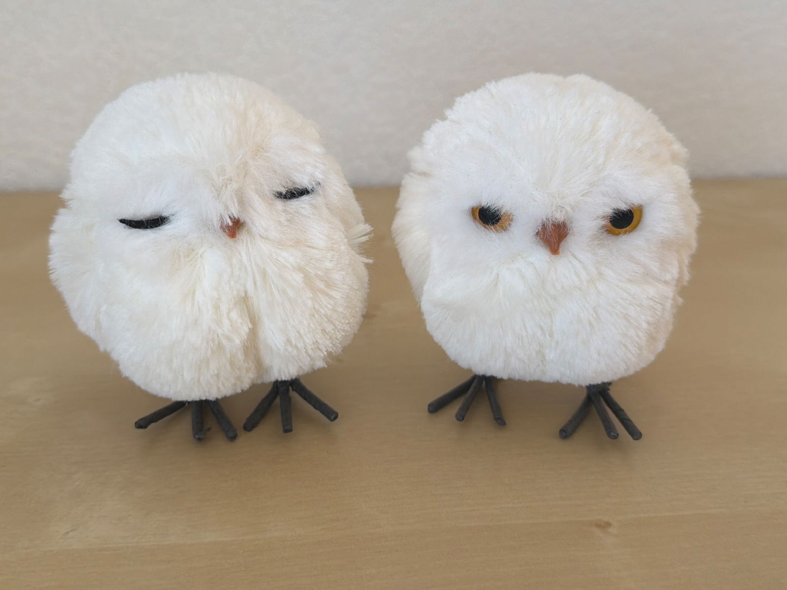 Two White Plush Owl Figurines With Metal Legs: Two white plush owl figurines featuring soft faux fur bodies and painted metal legs. Each owl has distinct facial expressions, adding personality to the pair. Suitable for decorative display. Dimensio