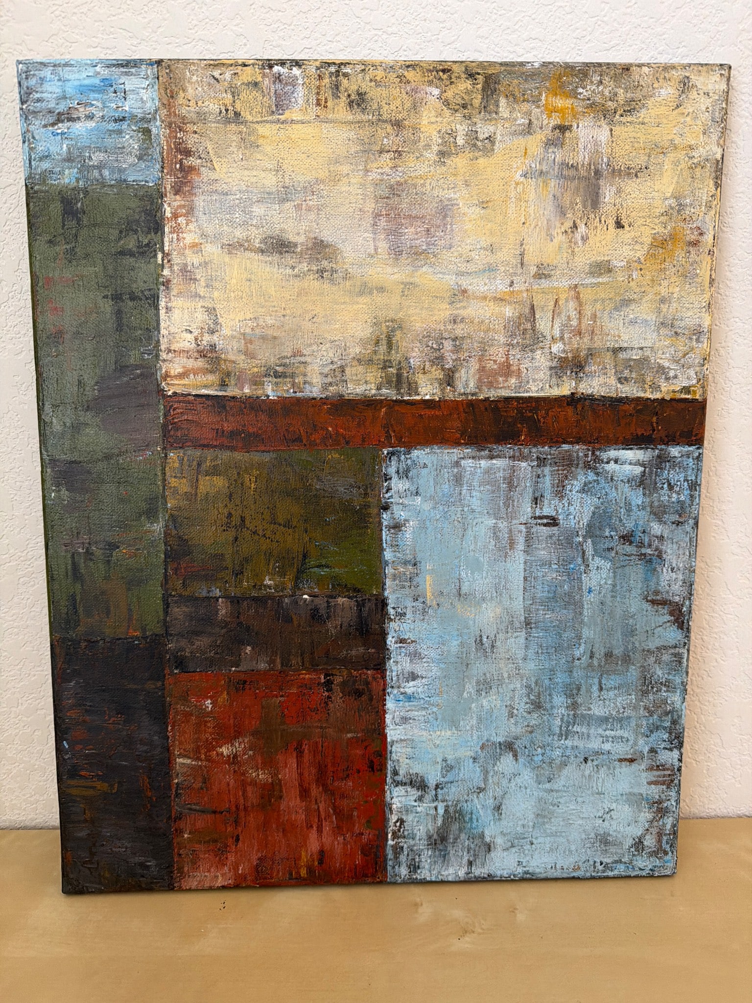 Abstract Acrylic on Canvas Painting with Wood Frame: Abstract acrylic painting on canvas featuring a geometric design with varying hues of blue, red, and earthy tones. The artwork is mounted on a wooden frame and displays visible textures and layering o