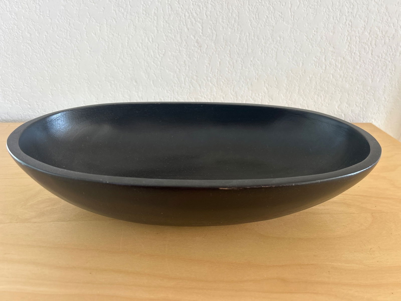 Vintage Black Oval Ceramic Serving Bowl: Vintage black oval serving bowl crafted from ceramic with a sleek and smooth finish. This bowl features a minimalistic design and is versatile for multiple uses. The underside shows signs of gentle we