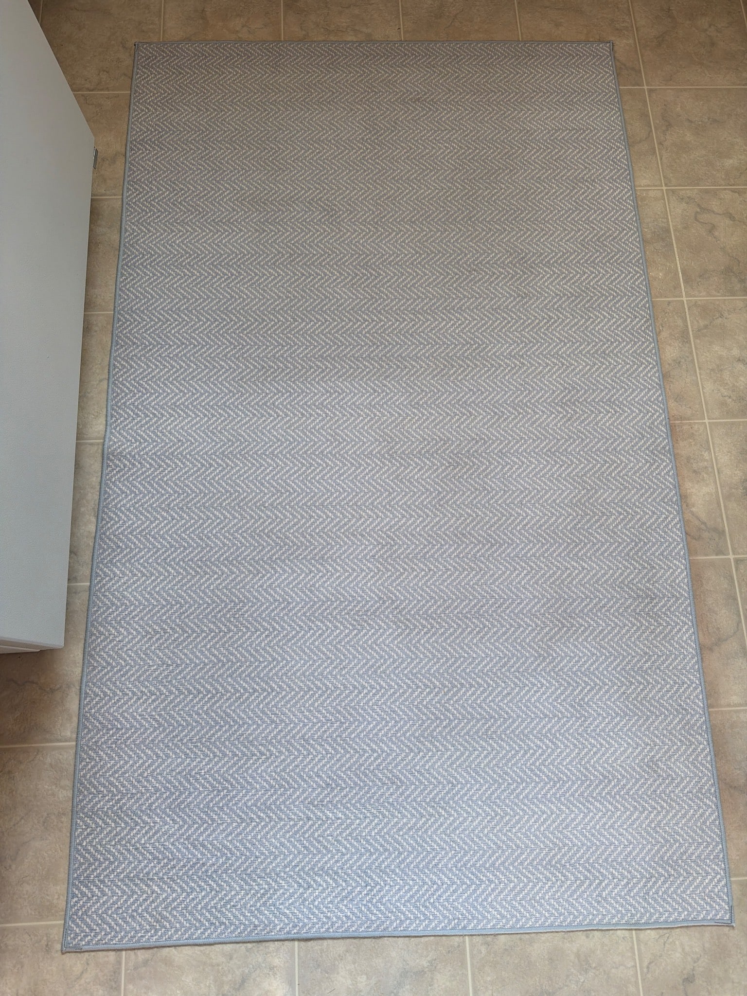 Gray Rectangular Area Rug With Subtle Chevron Pattern: A gray rectangular area rug featuring a subtle chevron pattern. Crafted with a durable weave, it is designed to complement a variety of interiors. The material and maker are unspecified. The rug is in