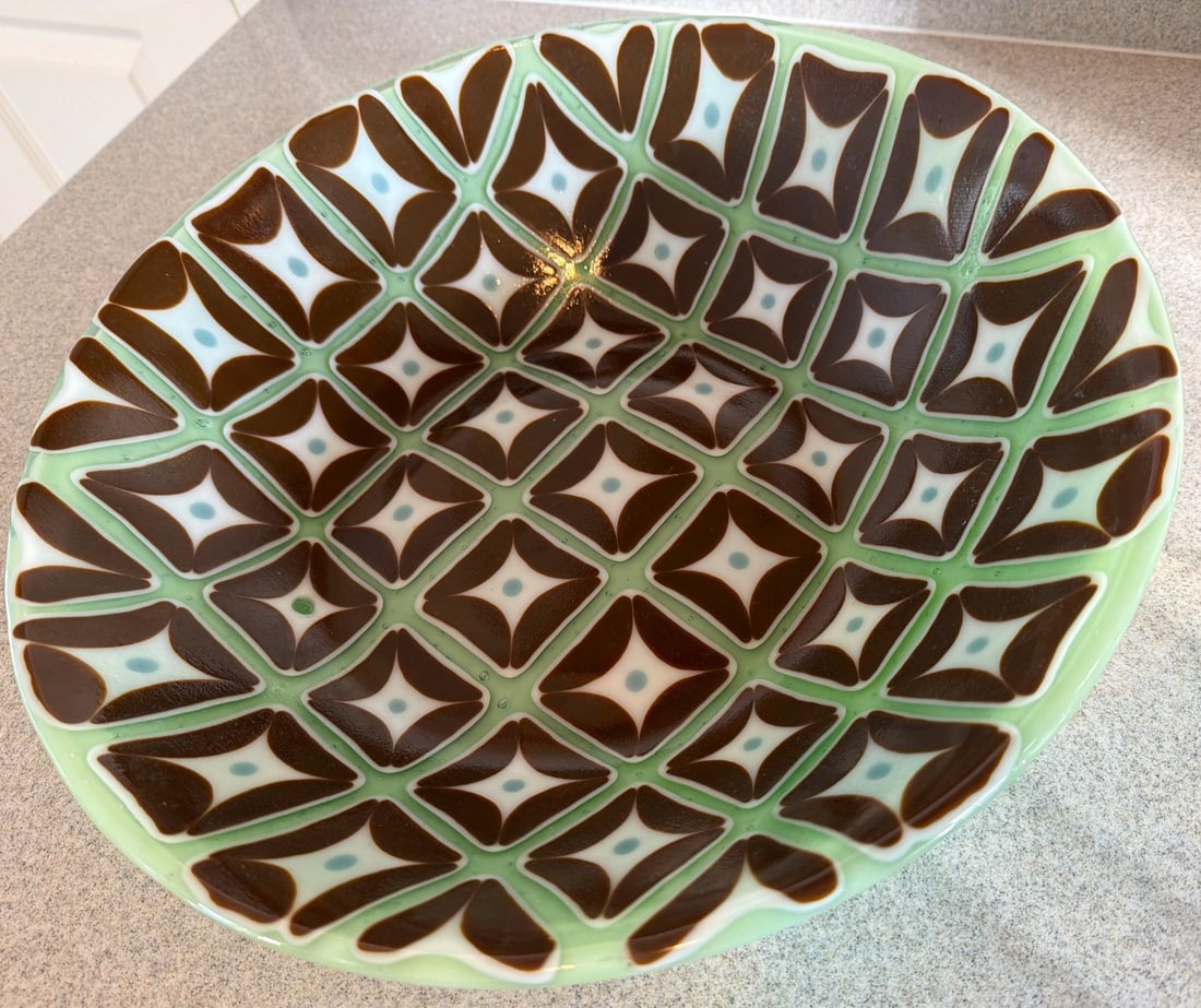 Vintage Green Ceramic Bowl With Brown Geometric Pattern: A vintage ceramic bowl featuring a green base with a striking brown geometric pattern on the interior. The design includes repeated diamond shapes with white accents, creating an eye-catching appearan