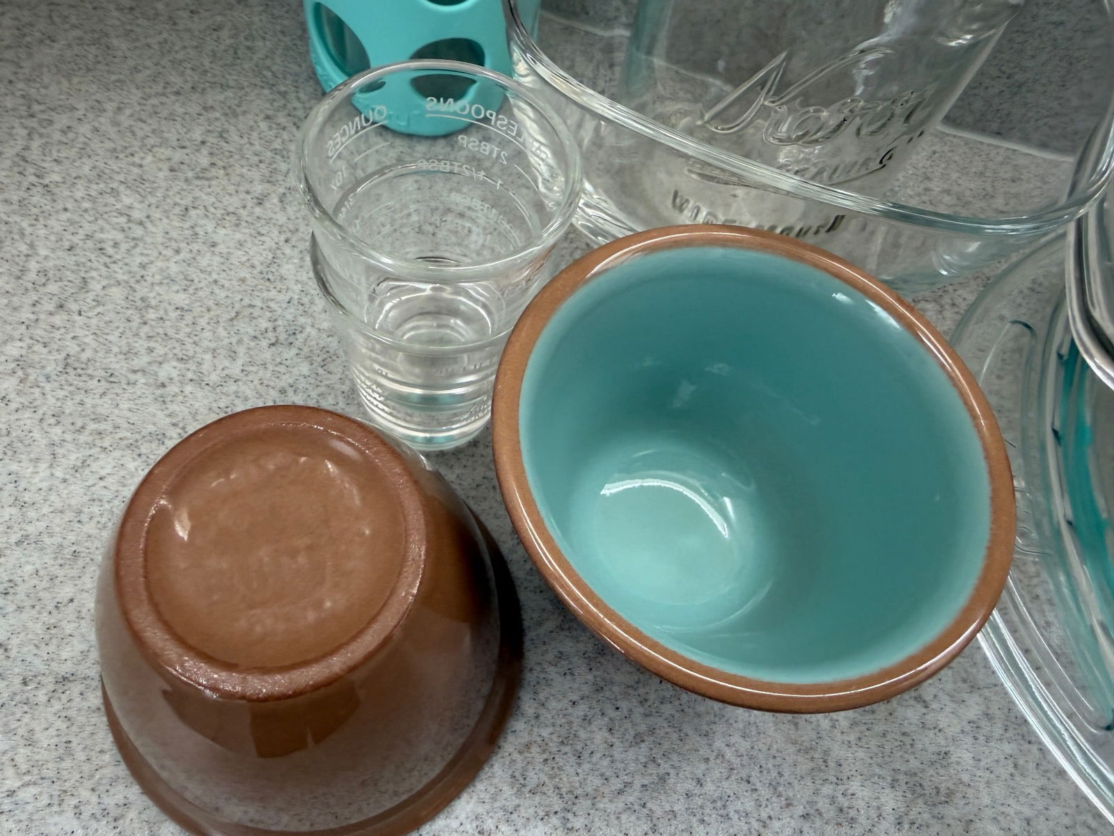 Glassware, Ceramic Bowls, and Drinkware: Lot featuring a variety of household items including a pair of ceramic bowls (one brown on the exterior and turquoise on the interior), multiple glass containers, a lidded glass casserole dish, stainl