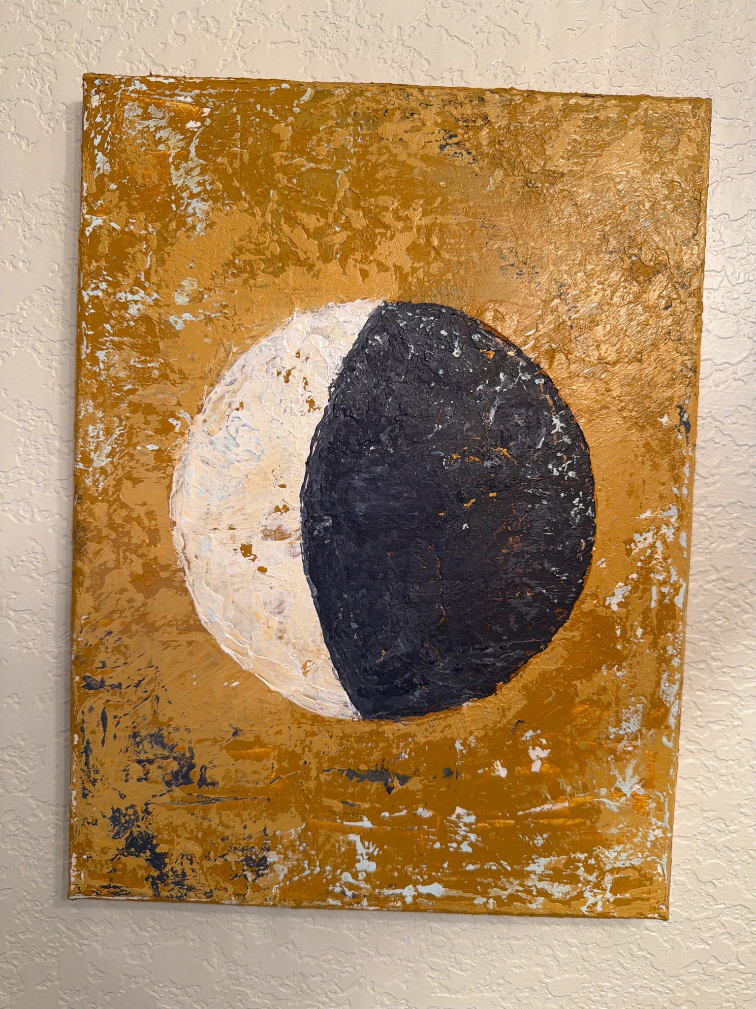 Abstract Painting Featuring a Half-Moon Design on Gold Background: Abstract painting showcasing a bold half-moon design with one half white and the other dark blue, set against a textured and vibrant gold background. The artwork appears to be done on a rectangular ca