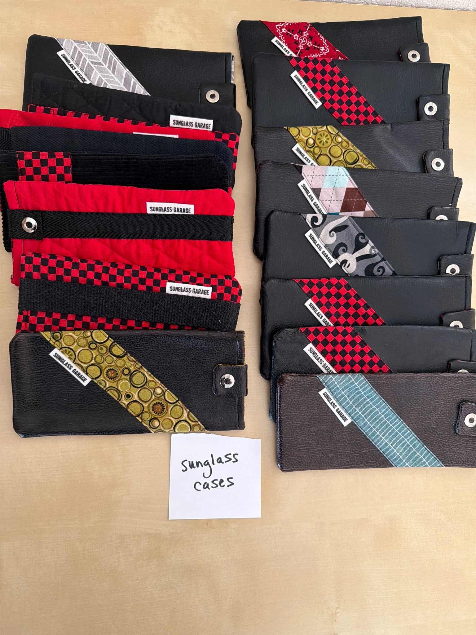 Handmade Sunglass Cases in Various Colors and Patterns: Handmade sunglass cases featuring multiple designs, patterns, and color combinations. Each case is crafted with fabric materials and features a snap closure. Includes a mix of red, black, and other pa