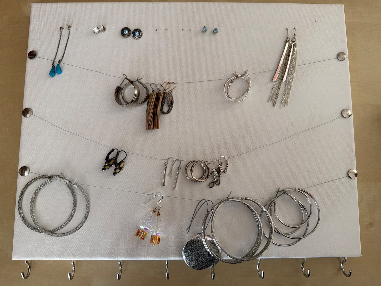 Earrings, Including Studs, Hoops, and Dangles: Women's earrings displayed on a panel, featuring a mix of styles, including hoop, stud, and dangle earrings with various materials and designs. Some include metallic elements, decorative beads, and ha