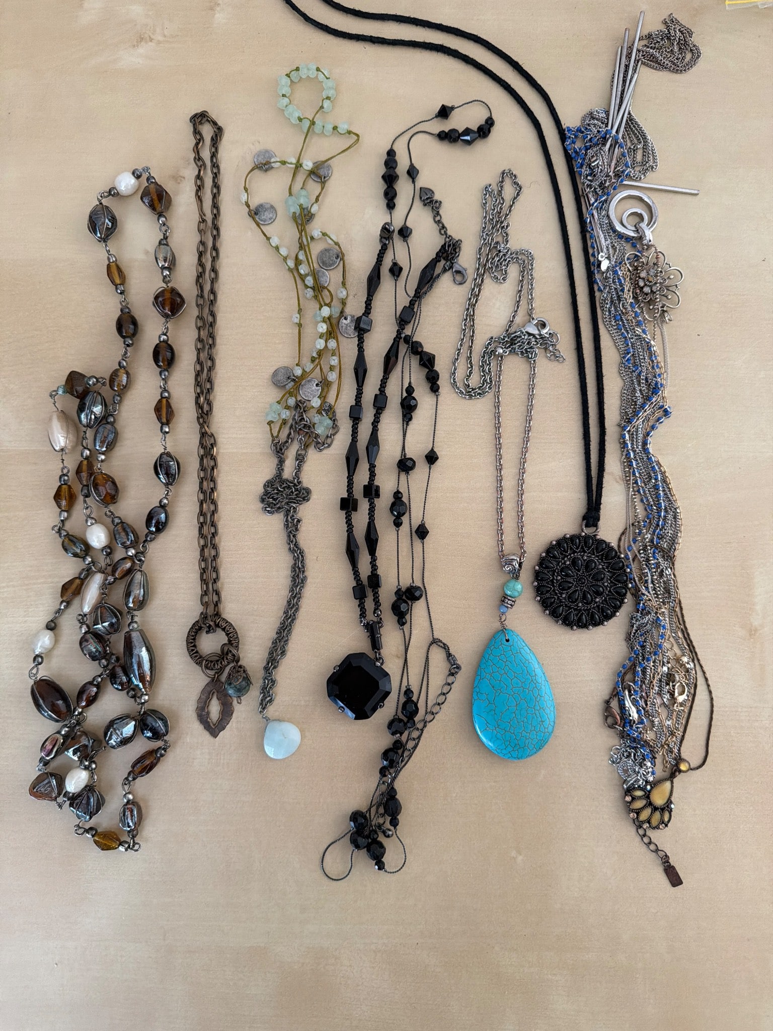 Beaded and Pendant Necklaces: Necklaces featuring a variety of designs, materials, and finishes. Includes beaded styles, chain-link necklaces, and pendant pieces such as a turquoise teardrop and black circular pendants. Materials