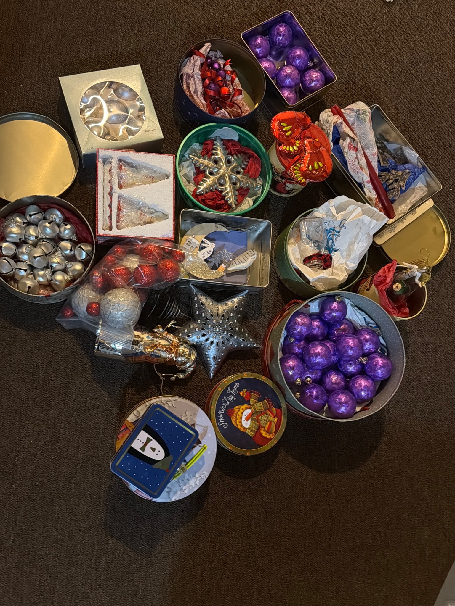 Christmas Ornaments in Various Styles: A large assortment of Christmas ornaments, including a mix of spherical ornaments, stars, and other decorative shapes in various colors and finishes, such as purple, red, and silver. Includes multiple