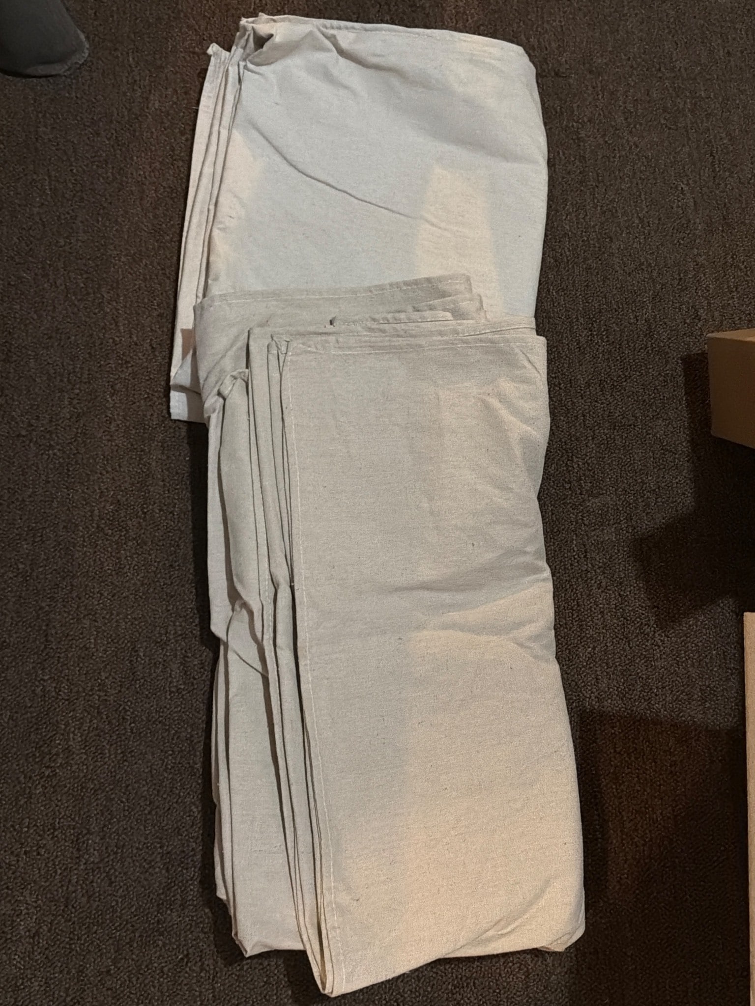 Painters Drop Cloth Material in Neutral Fabric: Neutral-toned painter's drop cloth material, suitable for covering floors or furniture during painting projects. The material is durable and typical of drop cloth fabric, designed to resist paint spil