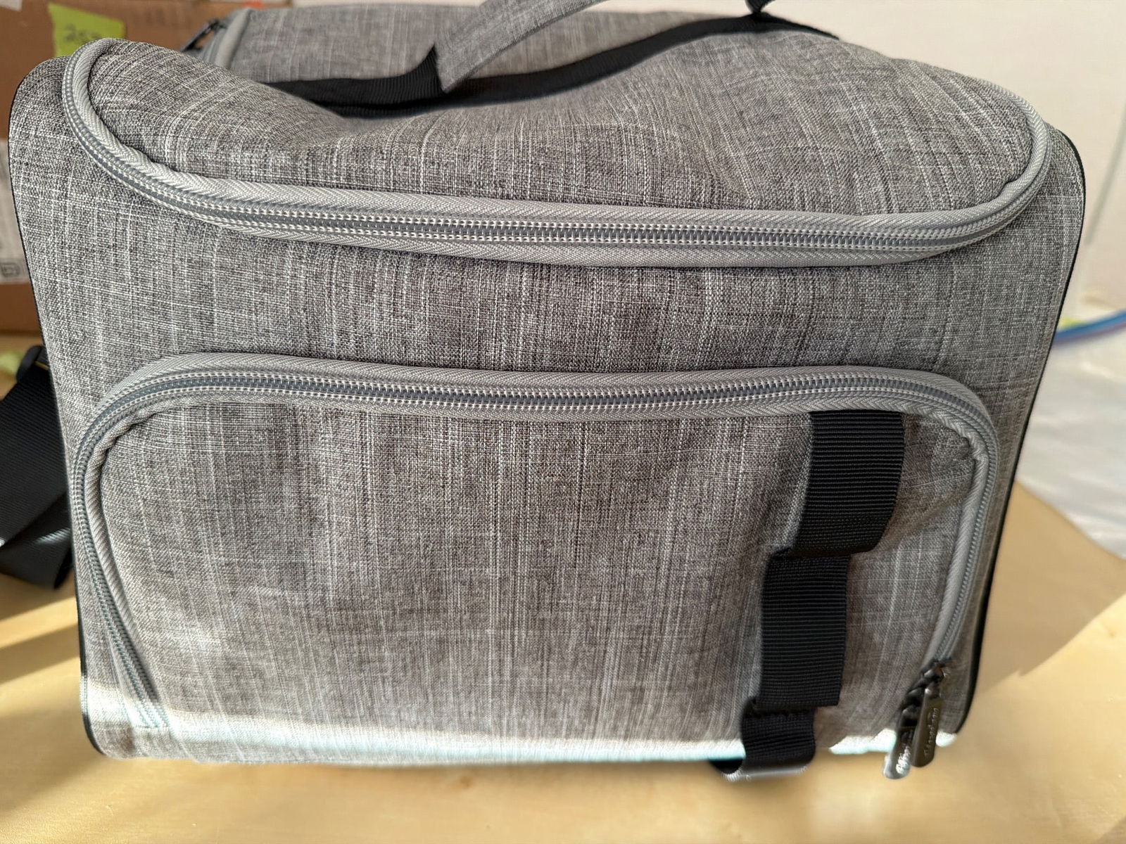 Gray Insulated Cooler Bag with Adjustable Strap: A gray insulated cooler bag with a durable fabric exterior, fitted with an adjustable shoulder strap and a top carry handle for portability. The bag features a zippered main compartment with a spaciou