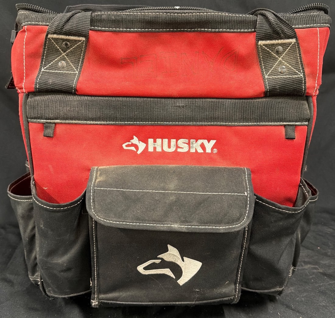 Husky Red and Black Rolling Tool Bag with Telescopic Handle: Husky rolling tool bag in a red and black fabric construction with black plastic wheels and a telescopic handle. Includes multiple pockets on the exterior and interior for tool organization. Interior