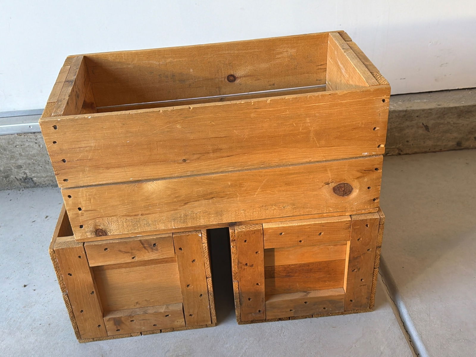 Three Wooden Crates with Rustic Finish: Three wooden crates featuring a natural, rustic finish. Constructed with sturdy wood and assembled using visible nails for added durability and charm. The set includes one larger crate and two smaller