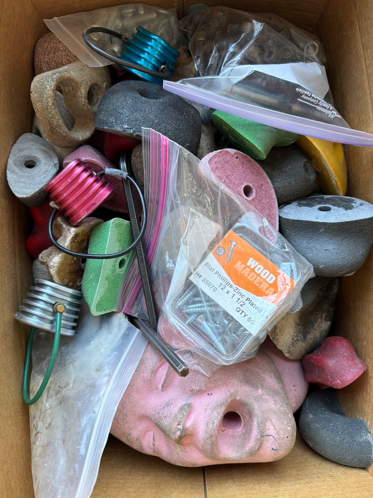 Climbing Wall Pegs and Holds with Mounting Hardware: Climbing wall components, including assorted pegs, variously colored and shaped holds, and mounting hardware. Several items are bagged for organization, including bolts and accessories. Suitable for b