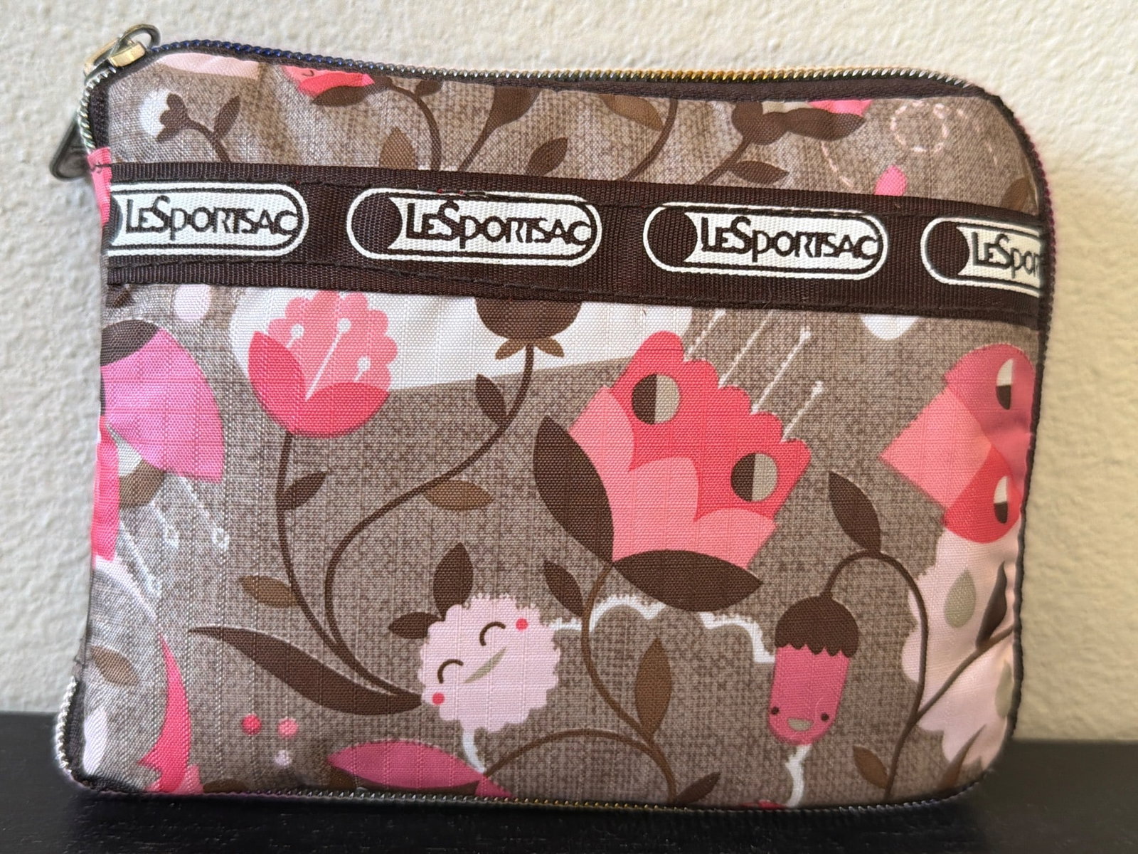 LeSportsac Zippered Pouch with Floral and Pink Owl Design: LeSportsac zippered pouch featuring a charming floral design with pink owls on a brown background. The pouch includes a durable zipper closure and a branded LeSportsac ribbon accent across the top for