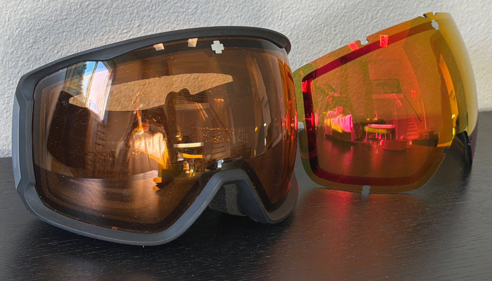 Spy Snow Goggles With Extra Lens: Spy snow goggles with a black frame and reflective orange lens. Includes an additional interchangeable reflective orange lens. Features adjustable black head strap with Spy logo. Suitable for snow spo