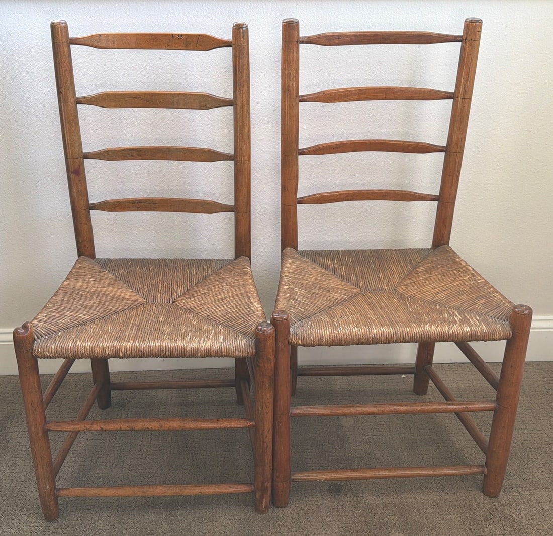 Vintage Wooden Ladder-Back Chairs with Rush Seats: Wooden ladder-back chairs featuring a traditional design with rush-woven seats. The chairs exhibit a warm wood finish, subtle patina, and sturdy ladder-back construction. Rush seats are intact, adding