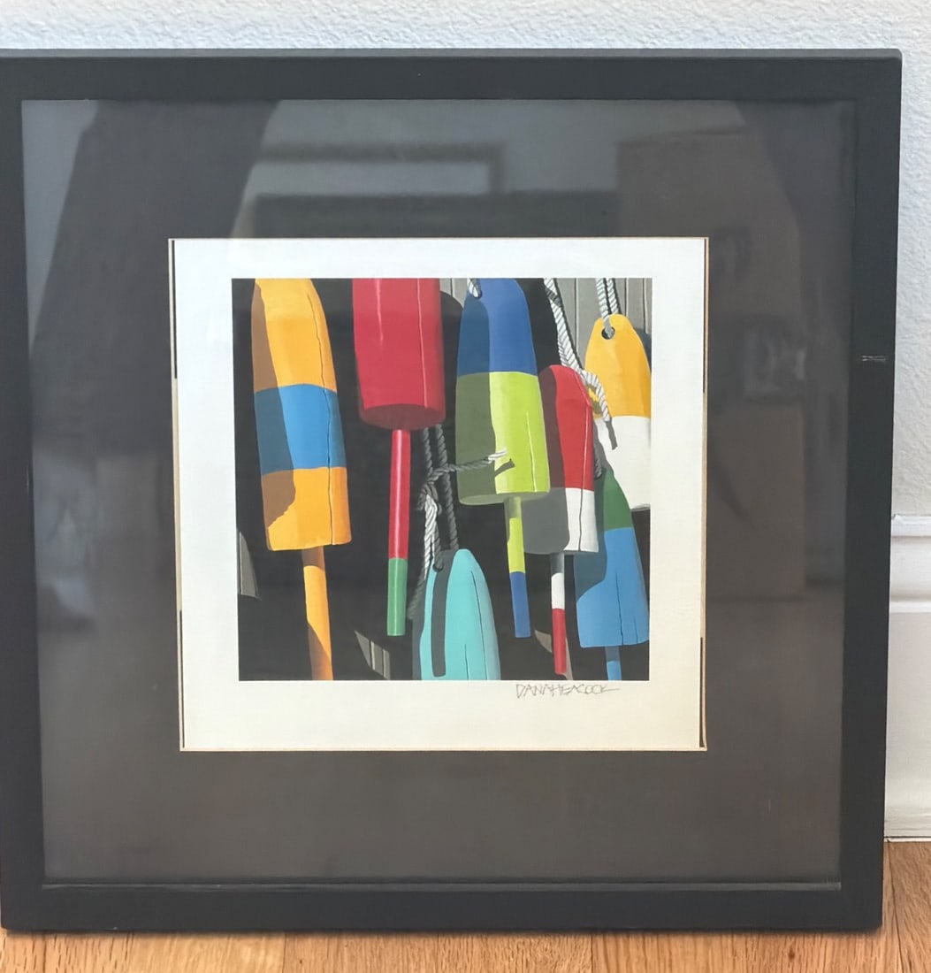 Framed Artwork Featuring Colorful Buoys by Dana Heacock: A framed artwork by artist Dana Heacock depicting colorful buoys against a dark background. The piece is presented in a black frame with a white mat and appears to be a reproduction print. Noted for i