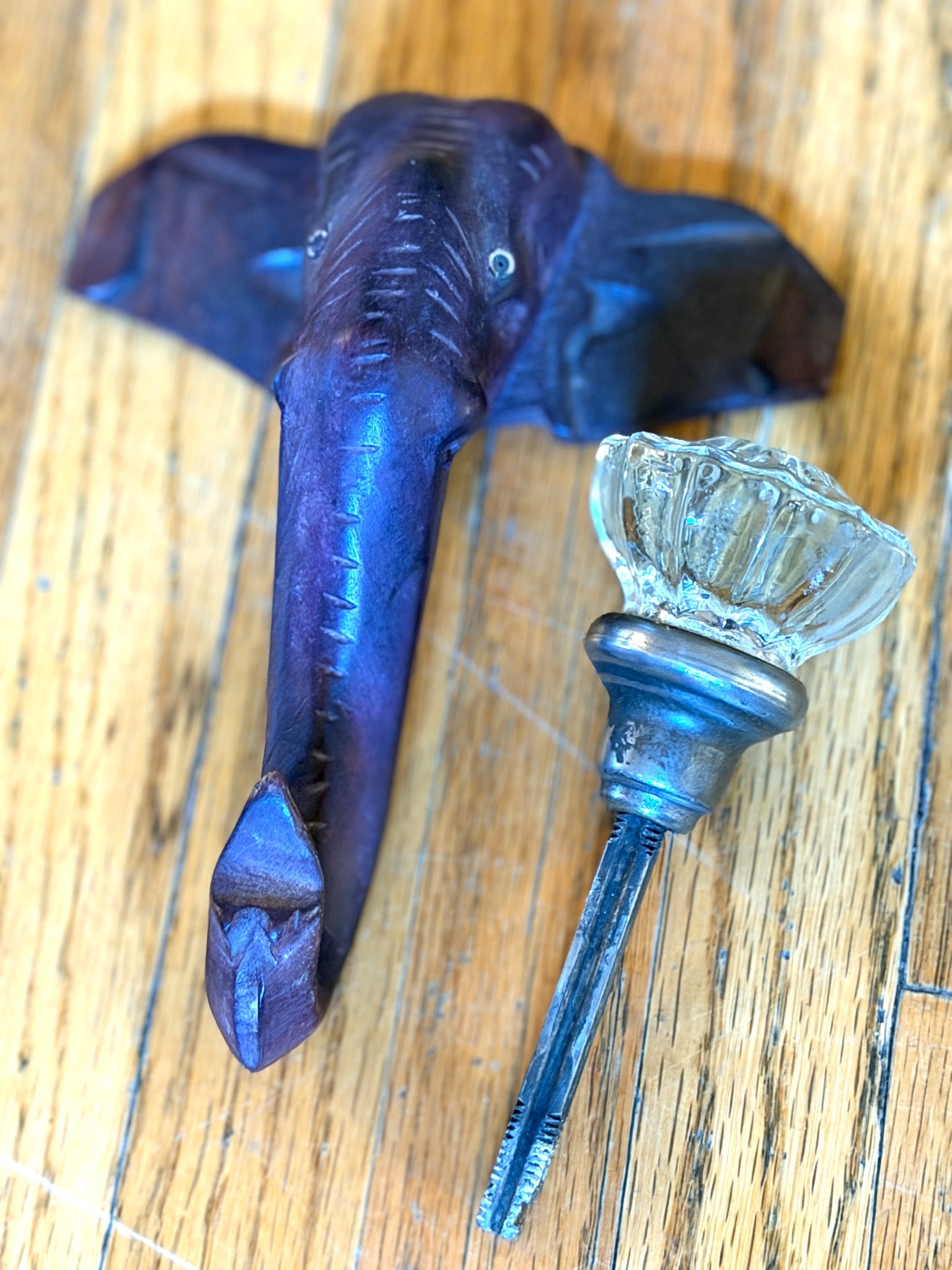Elephant Head Carved Wood Wall Hook With Glass Knob and Metal Mount: Elephant-shaped wall hook crafted from carved wood, featuring a polished finish. The hook includes a glass knob attached to a metal mounting shaft with a threaded base for secure installation. Notable