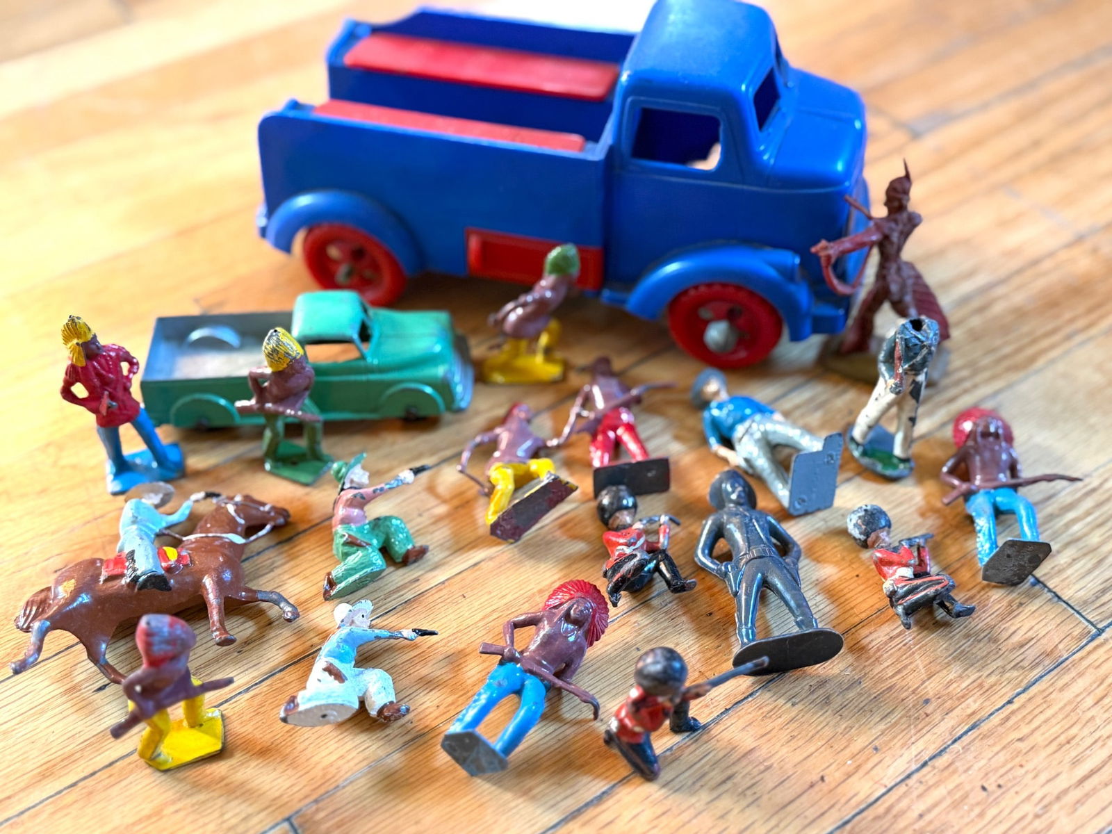 Painted Metal and Plastic Figures with Trucks and Horses: Painted metal and plastic figures depicting cowboys, Native Americans, and other characters. Includes a blue plastic truck and a green plastic car, as well as horses and accessories. The metal figures