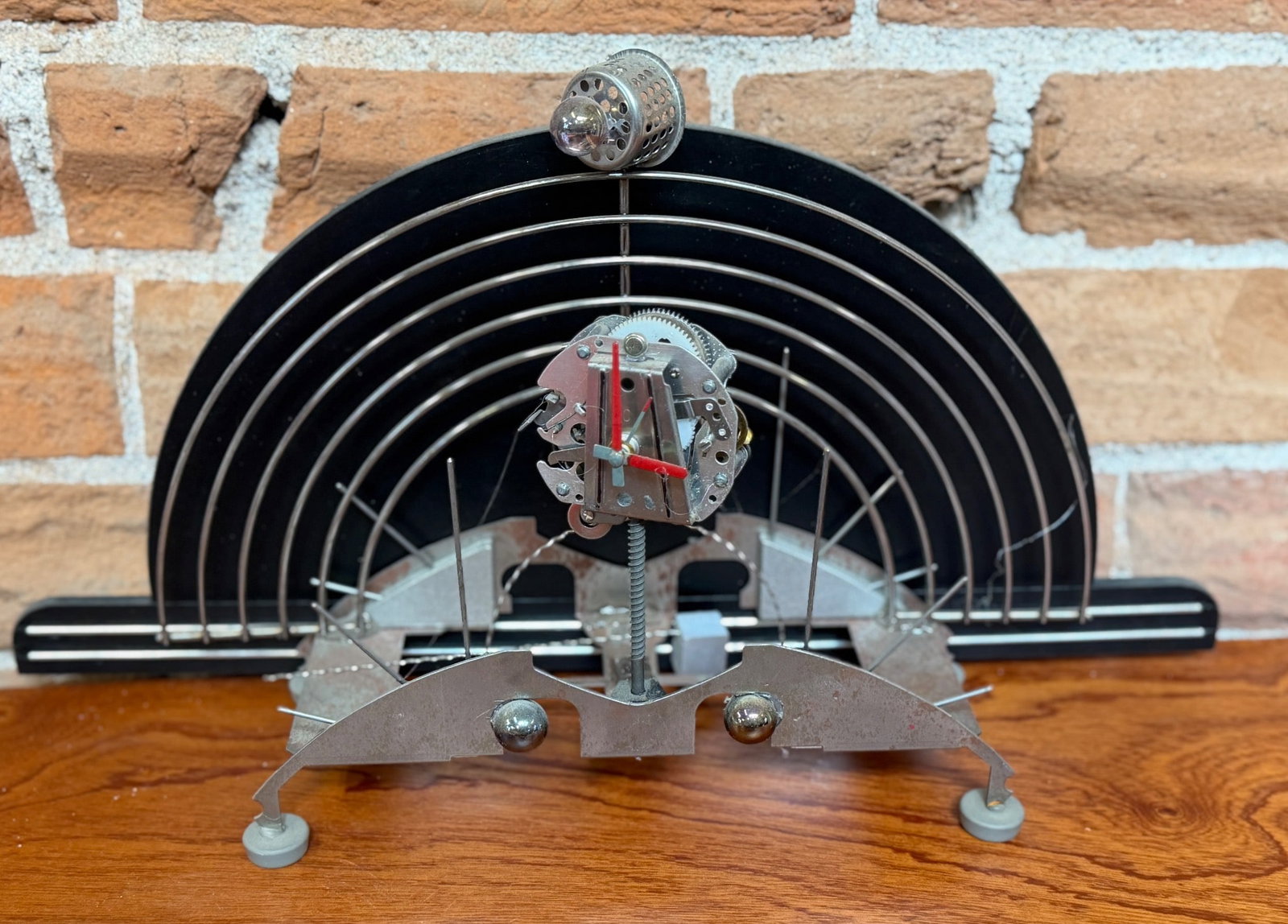Kinetic Metal Sculpture Desk Clock With Abstract Circular Design: Kinetic metal desk clock with an abstract circular design featuring multiple concentric rings and red clock hands. The sculpture incorporates metal parts with a dynamic and mechanical aesthetic and st