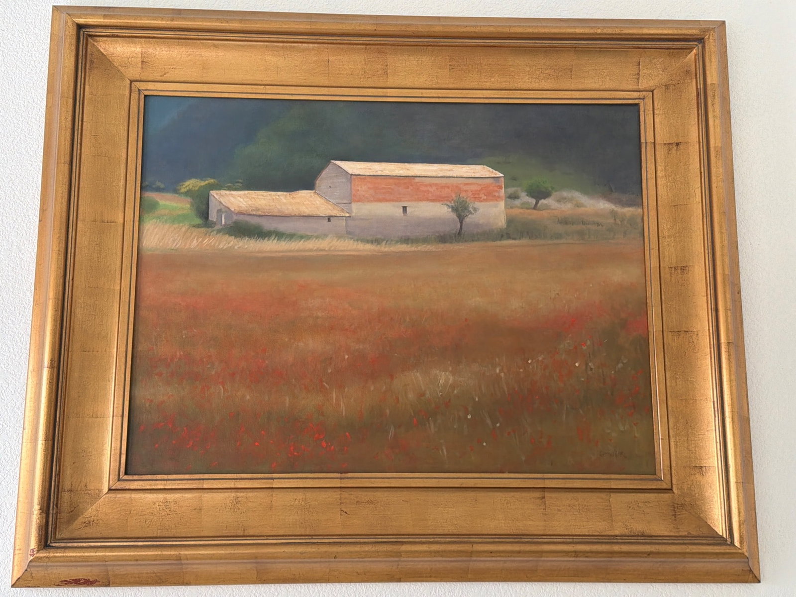 Framed Landscape Painting Signed ‘Kitchmer’: Framed landscape painting signed ‘Kitchmer’ in the lower right corner. The artwork depicts a rural scene featuring a barn amidst a field with red accents under a muted sky. The frame is gilded wit