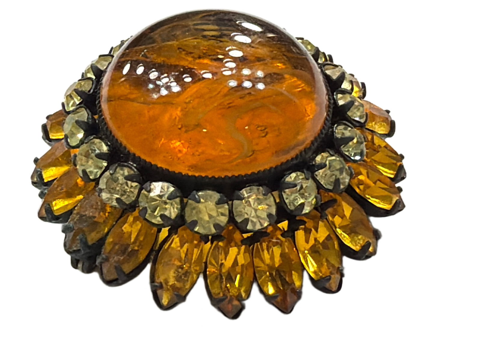 Amber-Colored Glass Brooch With Rhinestone Accents in Metal Setting: Amber-colored domed glass centerpiece surrounded by yellow rhinestones and mounted on a metal setting. The brooch is fastened with a pin-back closure. Suitable for decorative or wearable purposes, tho