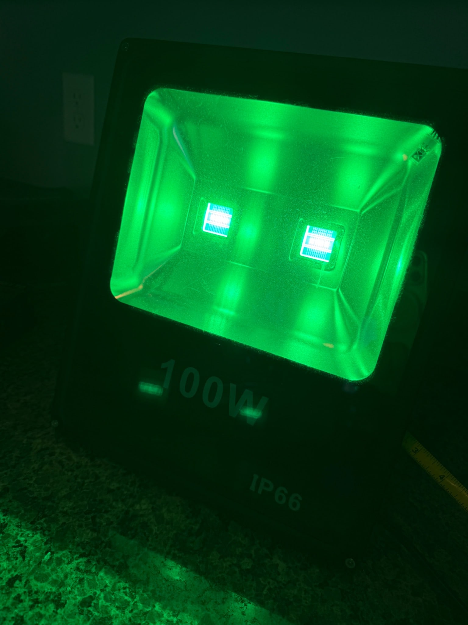 100W IP66 LED Floodlight in Black Housing: 100W LED floodlight with a black rectangular housing. Equipped with dual LED fixtures producing green light, suitable for outdoor use. Rated IP66 for water and dust resistance, ensuring durability in