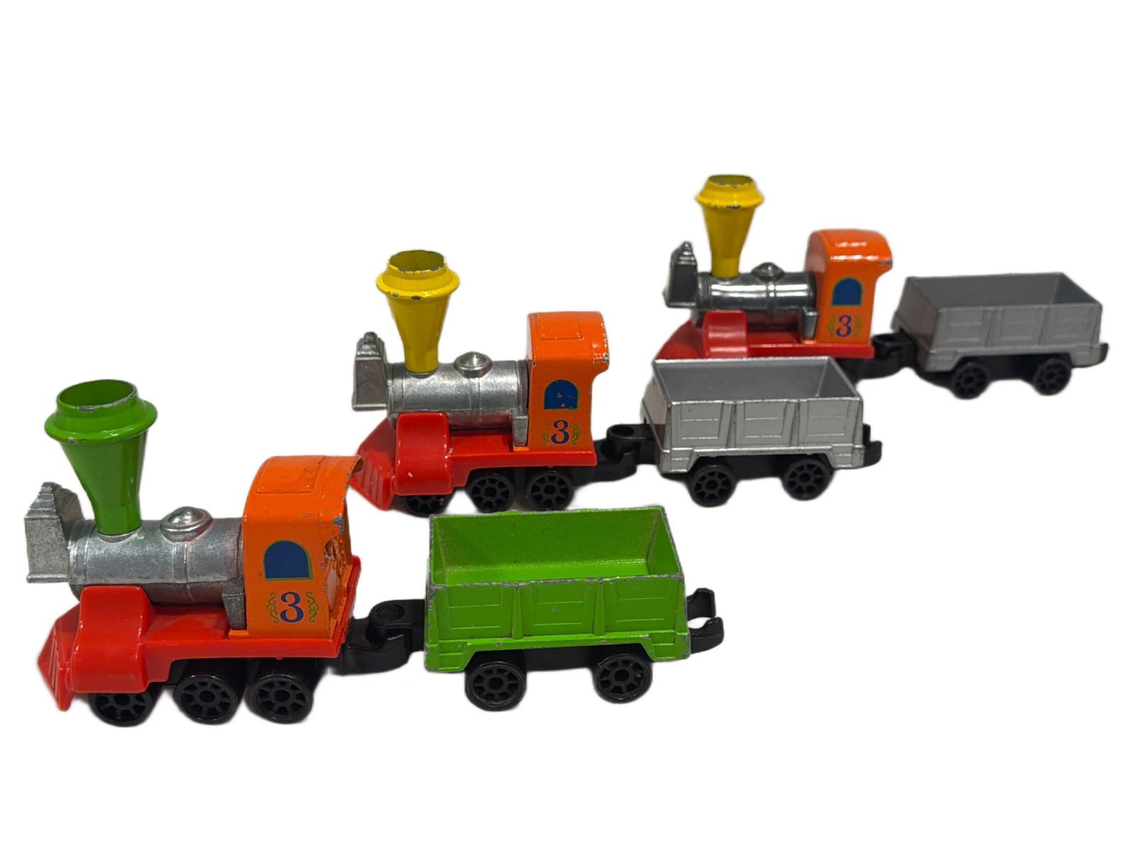Mattel Metal Toy Trains with Attached Cars, Set of Four: Four metal toy trains made by Mattel, each consisting of a vibrant locomotive and two attached cars. Locomotives are orange with colorful detailing and marked with the number 3. Some units feature add