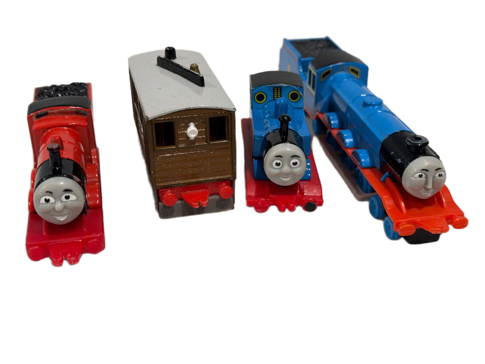 Thomas and Friends Die-Cast Train Figures Featuring Thomas, James, Gordon, and Toby: Four die-cast Thomas and Friends train figures including Thomas (Number 1), James (Number 5), Gordon (Number 4), and Toby the Tram. Each piece features detailed paintwork and design, with plastic and