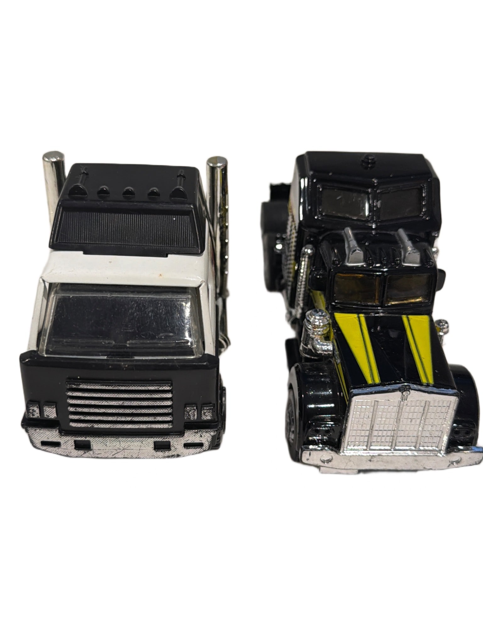 Two Die-Cast Truck Models Featuring NASA and Black-Yellow Designs: Two die-cast model trucks, including one white truck with ‘NASA USA 1786’ graphics and one black truck with yellow and chrome accents. Both trucks feature detailed cabin and trailer coupling desig