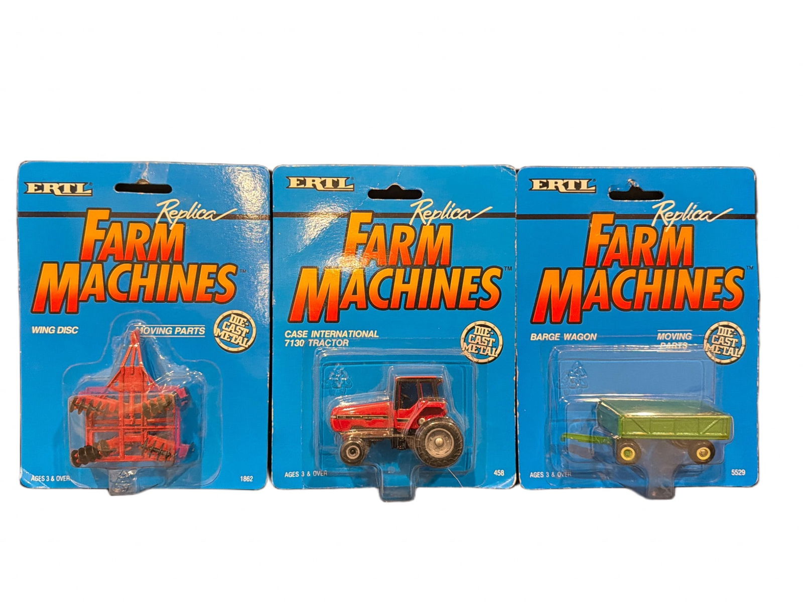 Ertl Replica Farm Machines Die-Cast Models in Original Packaging (3-Pack): Three Ertl Replica Farm Machines die-cast models, including a Wing Disc, Case International 7130 Tractor, and Barge Wagon. Each item is presented in its original sealed packaging and features ‘Repli