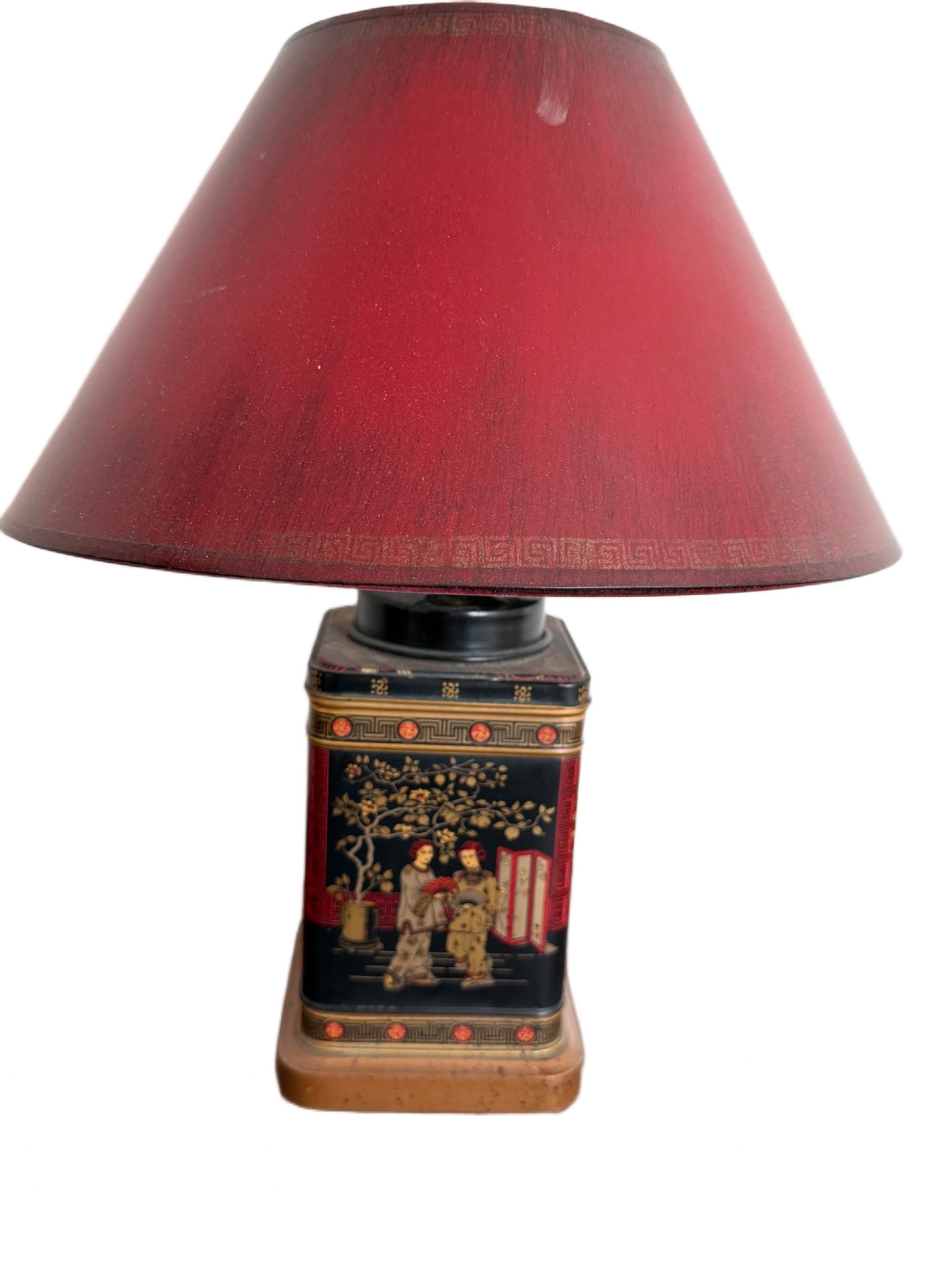 Decorative Table Lamp with Asian-Inspired Design: Decorative table lamp featuring an Asian-inspired motif with a detailed painted scene on the rectangular metal base and a red shade. The lamp rests on a wooden base and includes an electric cord. Meas