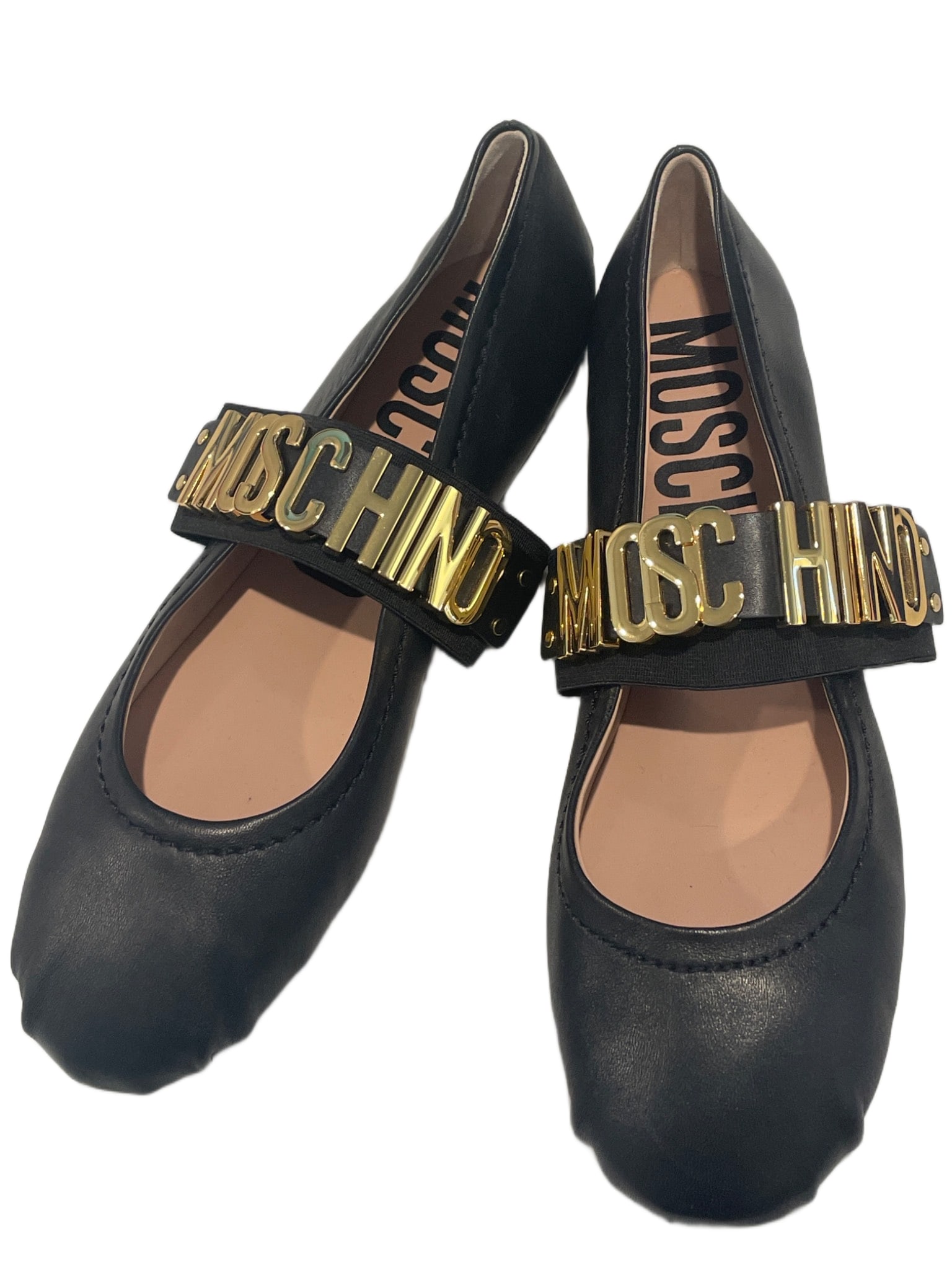 Moschino Black Leather Flats with Gold Logo Strap: Moschino black leather flats featuring a gold-tone metal logo strap across the top. Marked 'Made in Italy' and size 39 on the sole. The soles show light signs of wear, consistent with previous use. Th