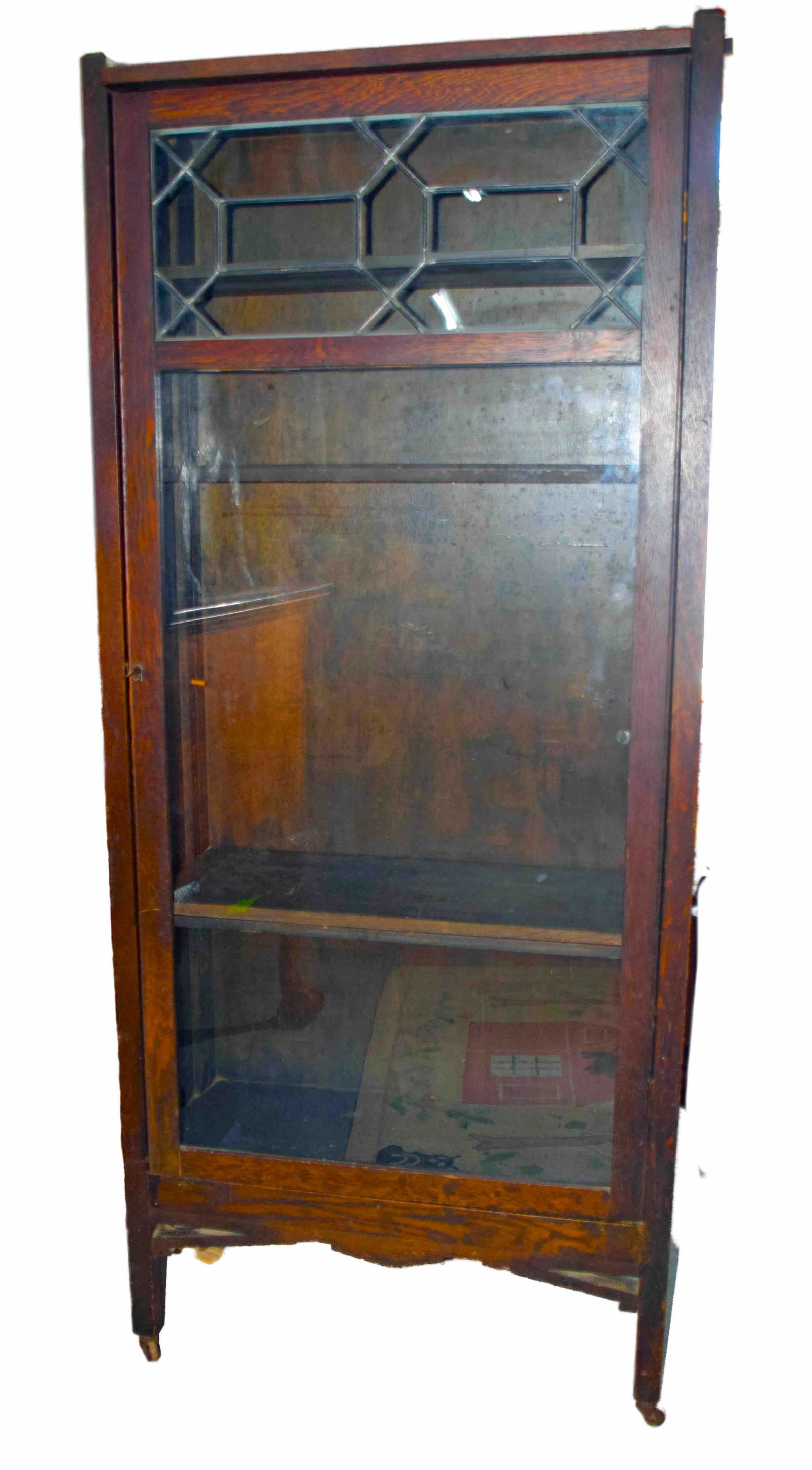 Oak Bookcase: Five shelves bookcase circa early 1900s with a lead glass pattern on top on small coaster wheels.. Dimensions: 64" height x 27" Width x 12" Depth.