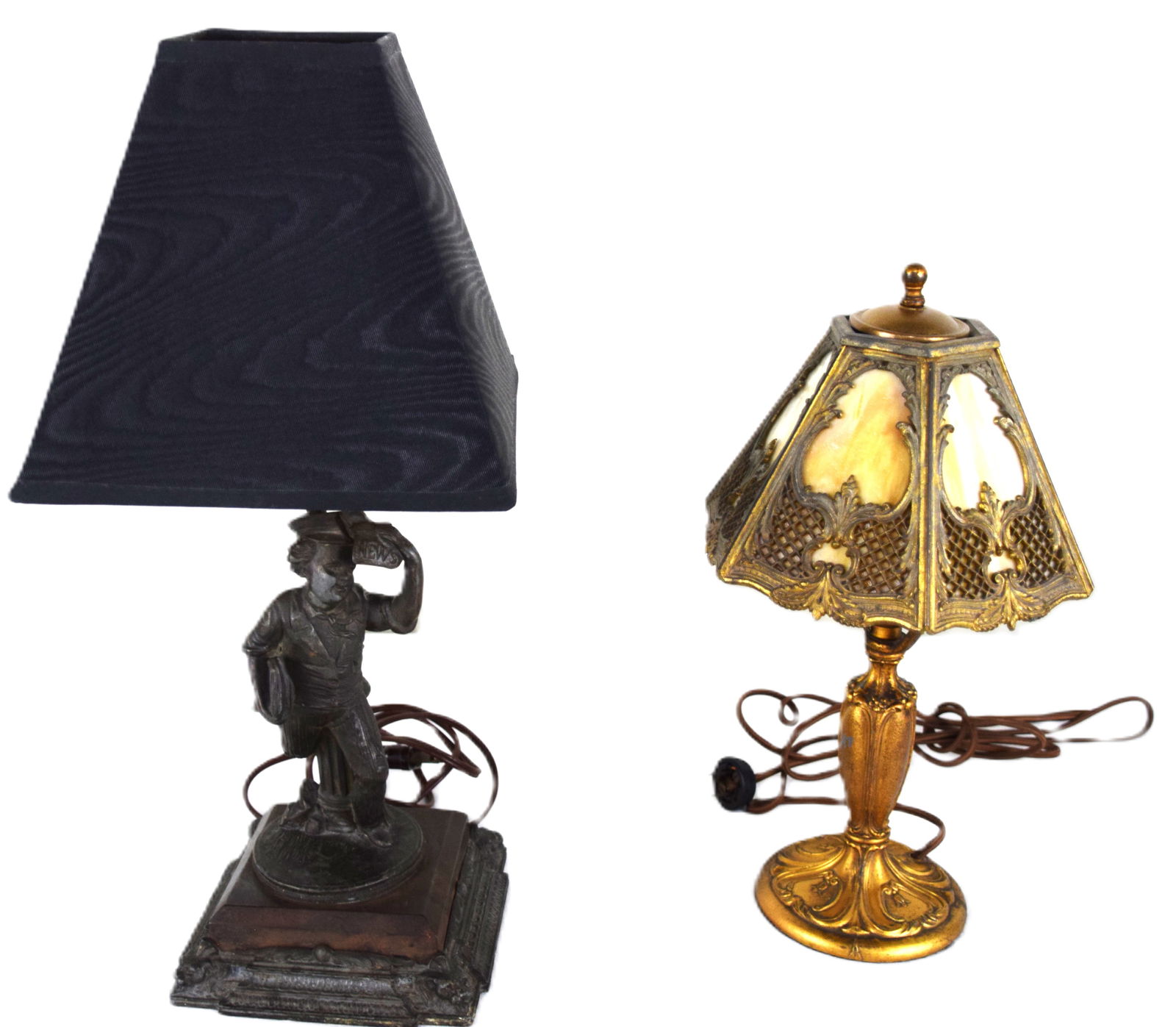 Lamp Lot: Figural cast lamp of a newspaper boy with linen shade (17" height) along with a slag panel desk lamp (13" Height).