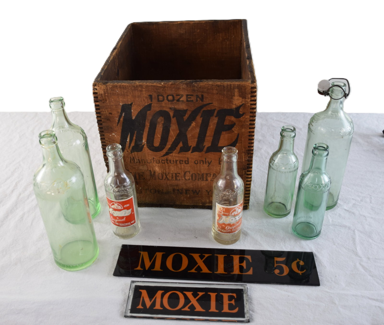 Moxie Collection: Moxie collection to include an advertising box, seven bottles and two glass signs.