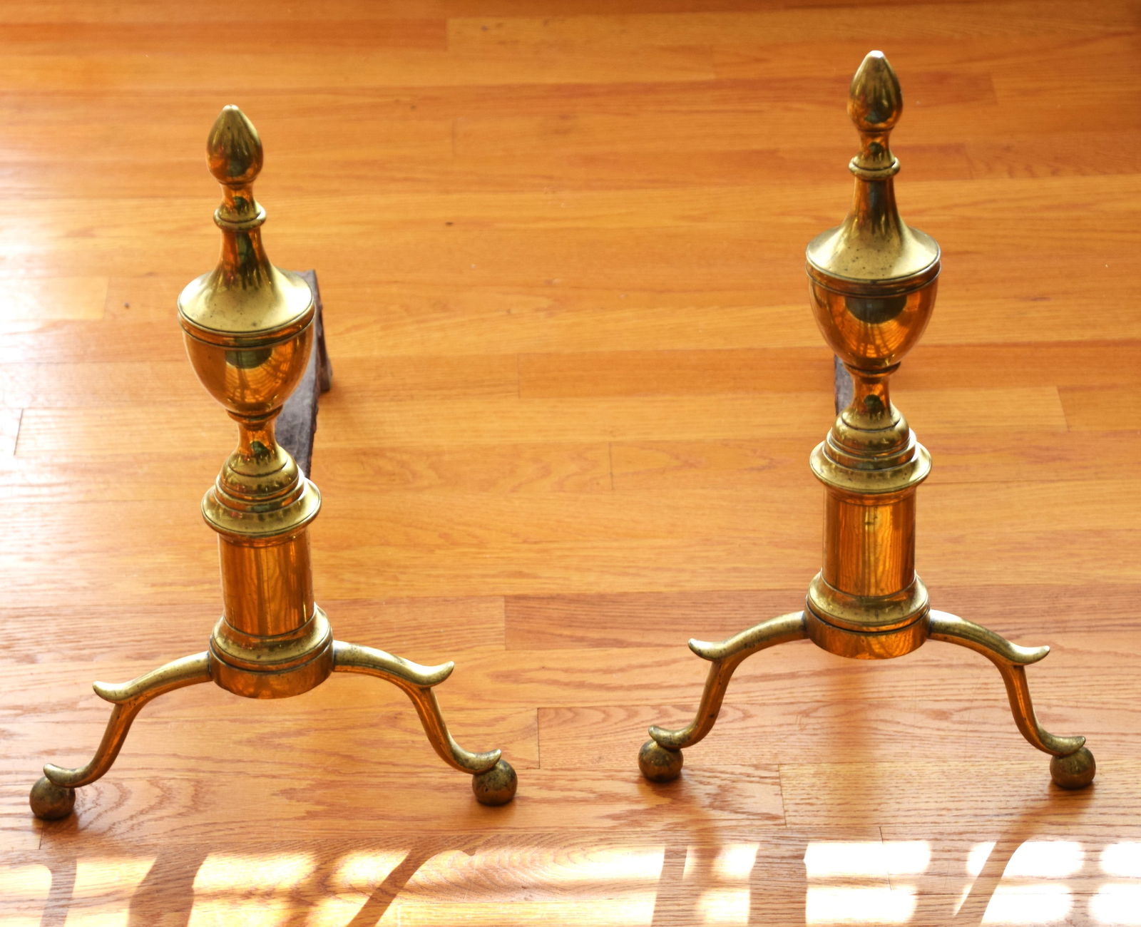 Pair of 18th Century Andirons: Pair of 18th Century steeple top brass andirons with the early stem and ball feet, from a New London NH home. John Nicols provenance. Dimensions: 17" H x 18" L