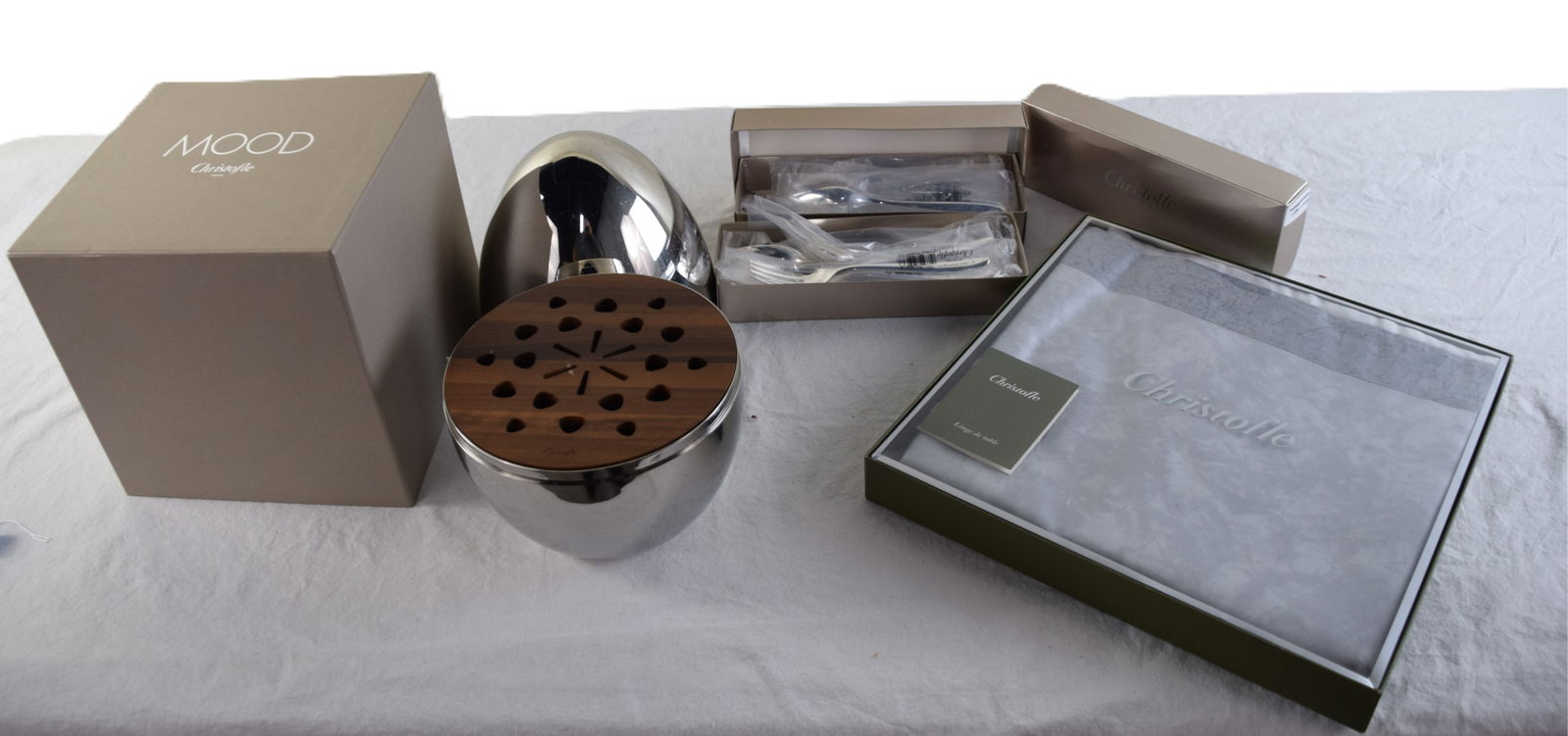 Christofle Lot: Silver-plated flatware set contains 6 table knives, 6 table forks, 6 table spoons, and 6 teaspoons. A decorative silver egg-shaped case with a Walnut Wood interior disk stores the cutlery. Also includ