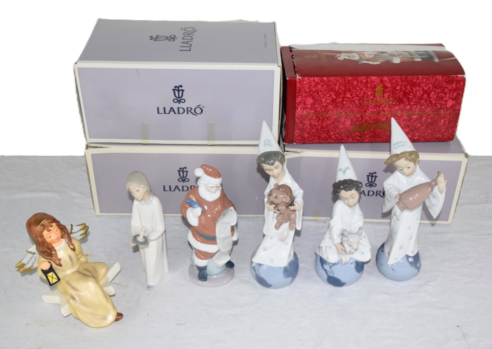 Five Lladro Figures: Five Lladro figures to include boy with cap and Lion toy (Leo), Girl with toy ram (Aries) and a girl with a water jug (Aquarius) all with original boxes, a Lladro Santa Claus with original box, a Llad