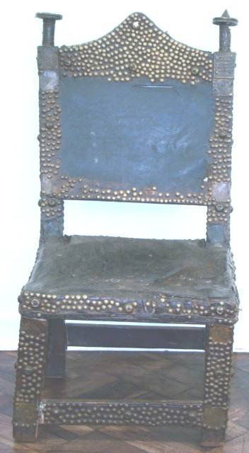 ANTIQUE ASHANTI CEREMONIAL CHAIR: ANTIQUE ASHANTI CEREMONIAL CHAIR, with a leather seat and back, with brass finials on the back (one point missing) , with brass beads, and worked brass decoration on the wooden frame. 74.5cm tall.
