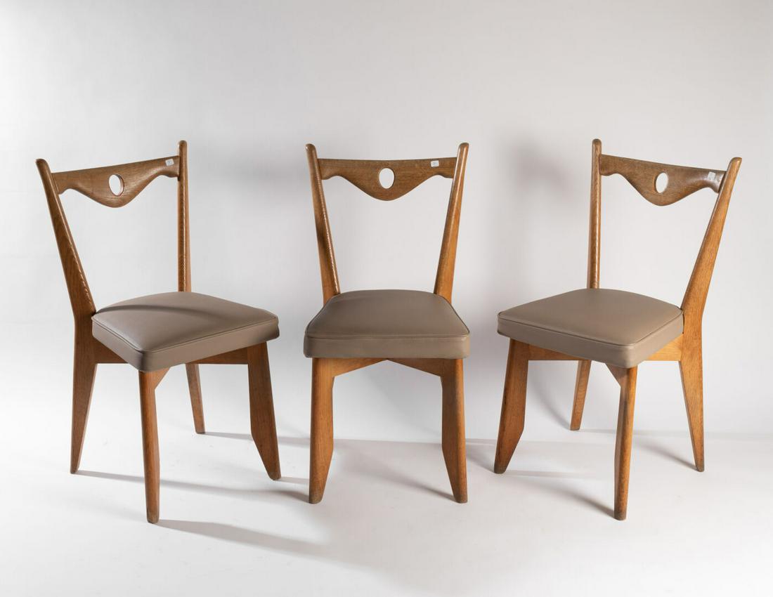 Robert GUILLERME (1913-1990) & Jacques CHAMBRON: Suite de six CHAISES, le dossier à ligne mouvementée repercé d'un oval Chêne clair, garniture de skaï gris H. 88 cm. L. 45,5 cm Usures à la patine