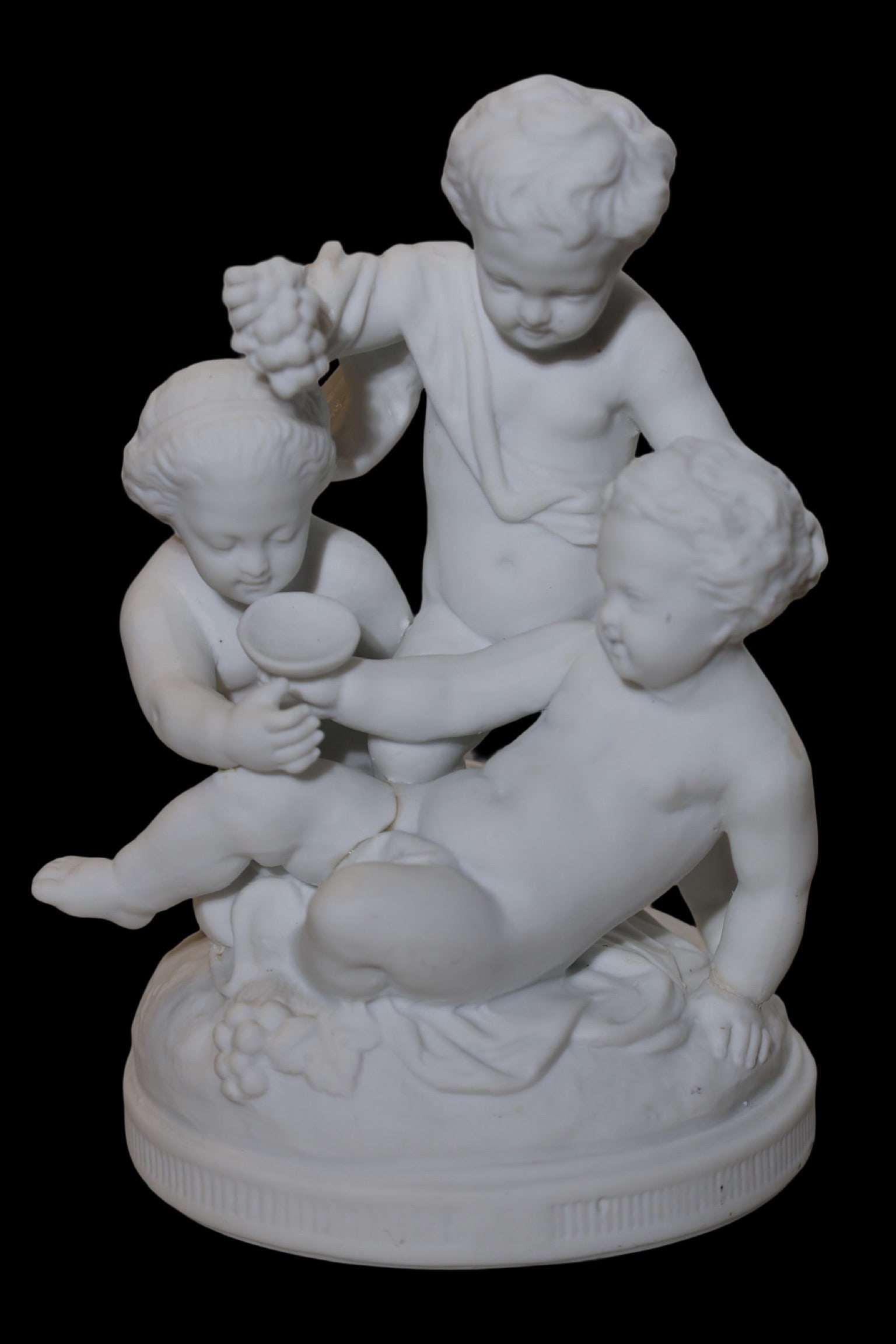 20th century Manufacture nationale de Sèvres, Children and Bacchus. Bisque porcelain: Manufacture nationale de Sèvres, Children and Bacchus. Bisque porcelain On an oval base are the three children's figures, one reclining, another seated and the third standing. The grapes, clusters, l