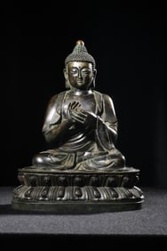 A seated statue of a copper burning lamp Buddha