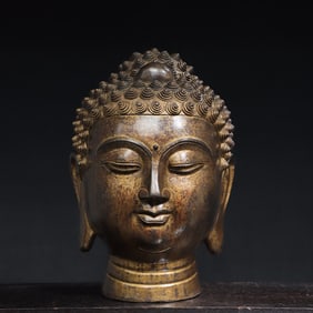 A bronze and gold statue of the head of the Buddha