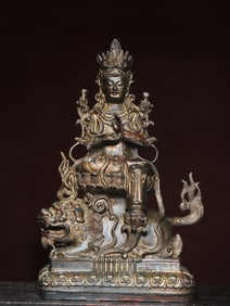 A bronze and gold statue of Manjushri Buddha