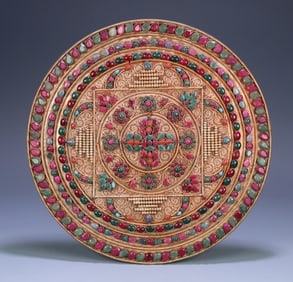 A piece of copper filigree inlaid with gemstones