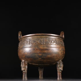 A bronze tripod with animal face pattern