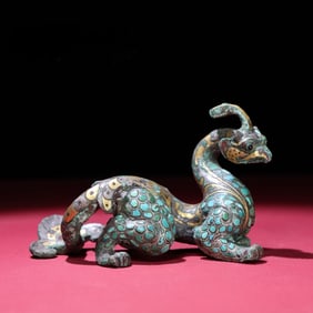 A bronze ornament inlaid with gold, silver, and gemstones