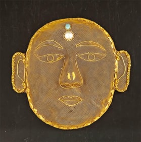 A copper-gilt filigree humanoid mask