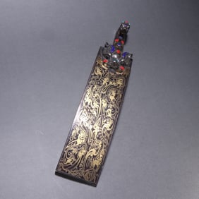 A piece of bronze and silver inlaid with gemstones from the Han Dynasty with a hook
